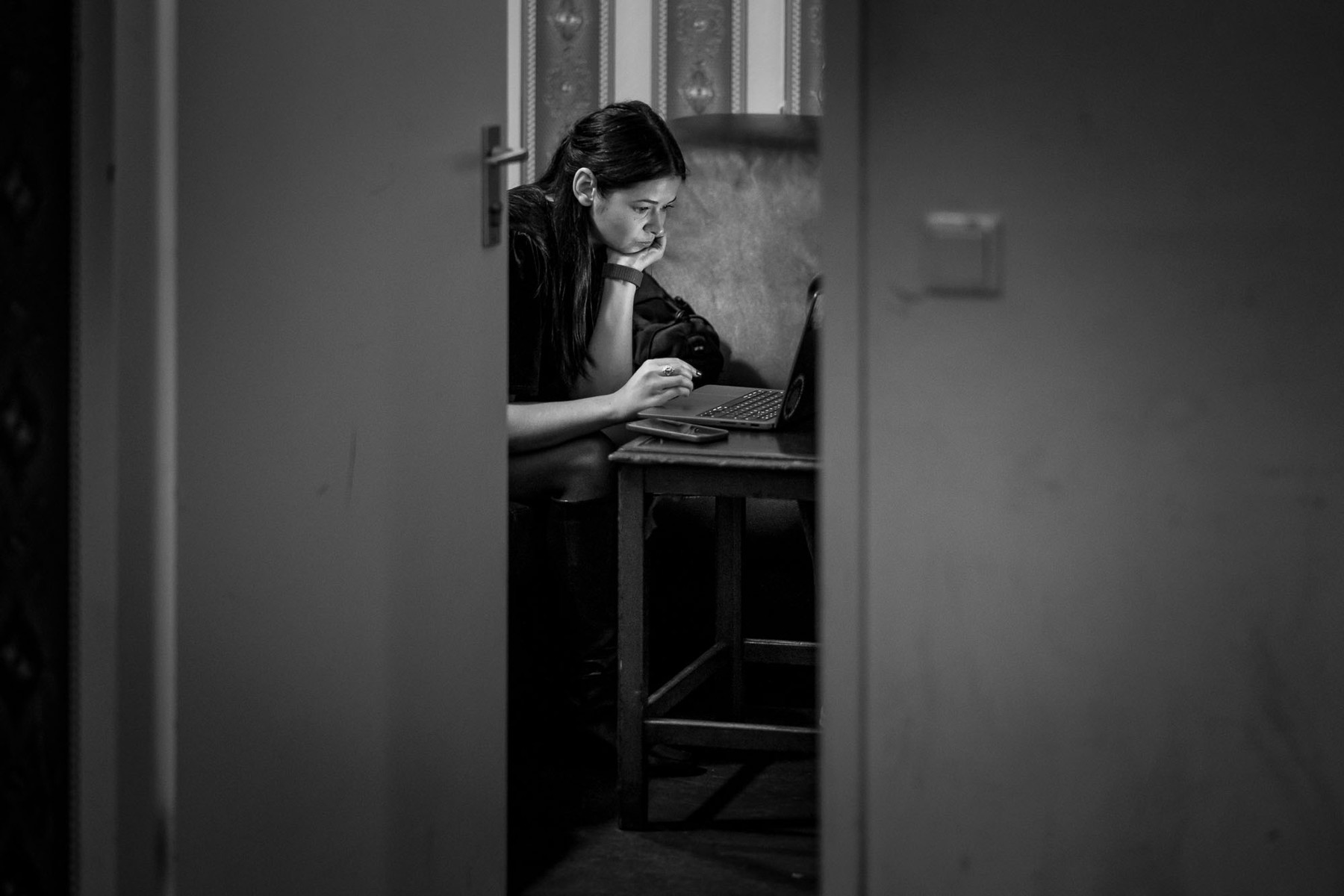 A black and white photo of Ana Rodrigues at beyond tellerrand. Shot through a half open door and it seems as if she is preparing last bits for her talk.