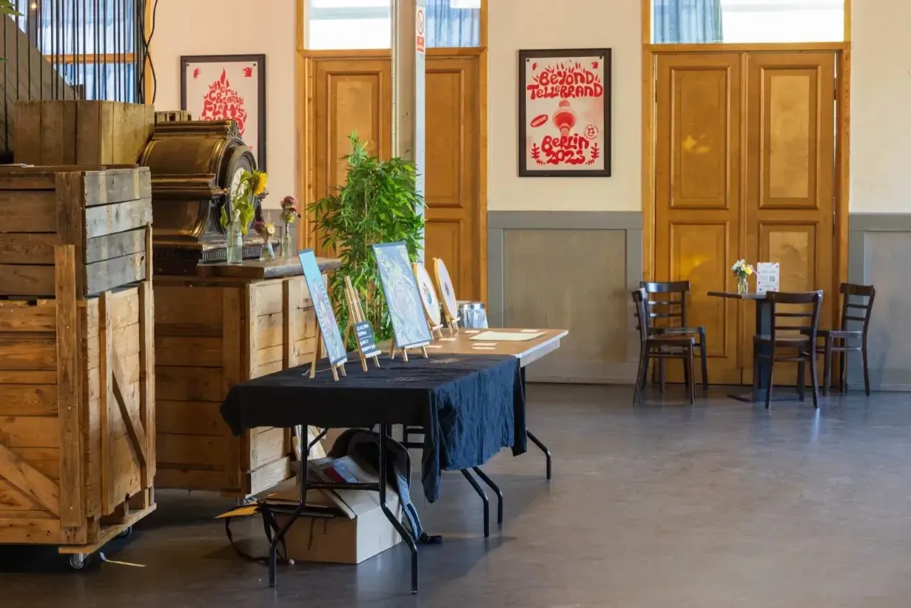 The photo shows the exhibition area of the conference. On the wall you can see two of the posters designed by Mike Kus. Printed in red on white paper.