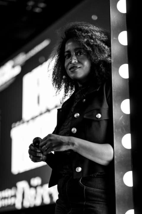 Sharon Steed leaning against the frame of the stage filled with light bulbs, waiting to get on stage.