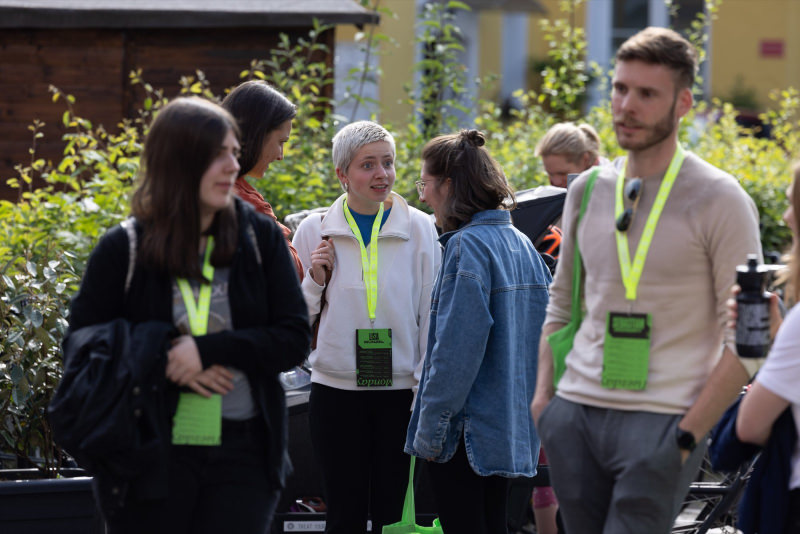 A group of people standing outside of the theatre in the sunshine during a break. You can spot 7 people in the photo. 7 women, one man.