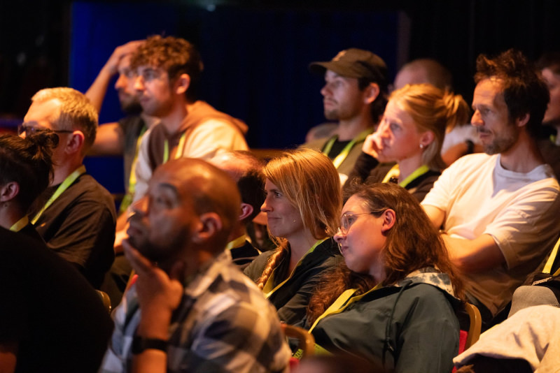 The audience in the theatre listening to and watching a talk.