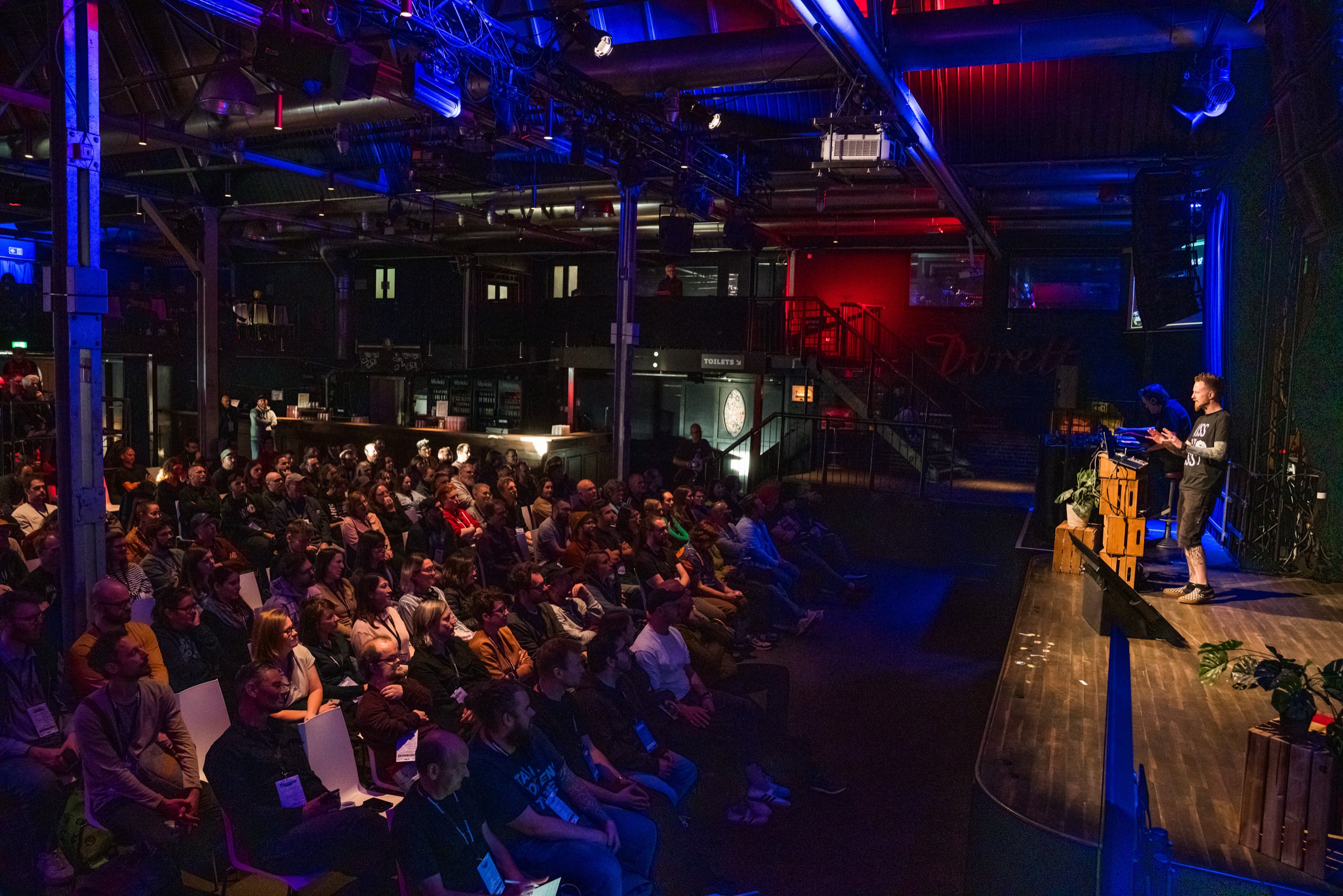 A photo of beyond tellerrand Berlin by Christian Burkert. Adam Argyle on stage in front of the audience.
