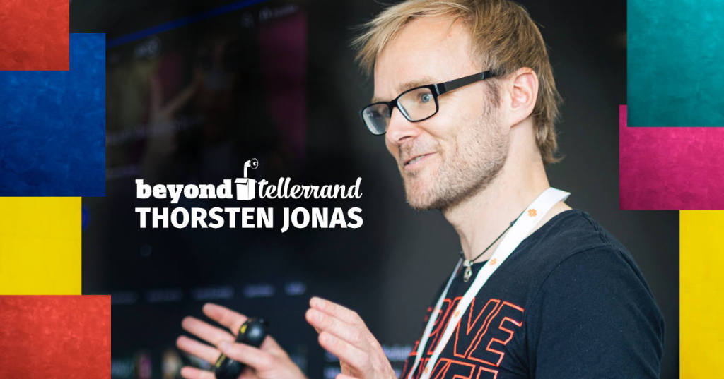 A photo of Thorsten Jonas lecturing. The photo is taken from the left side and you see him gesturing with his hands as if he explains something to someone.