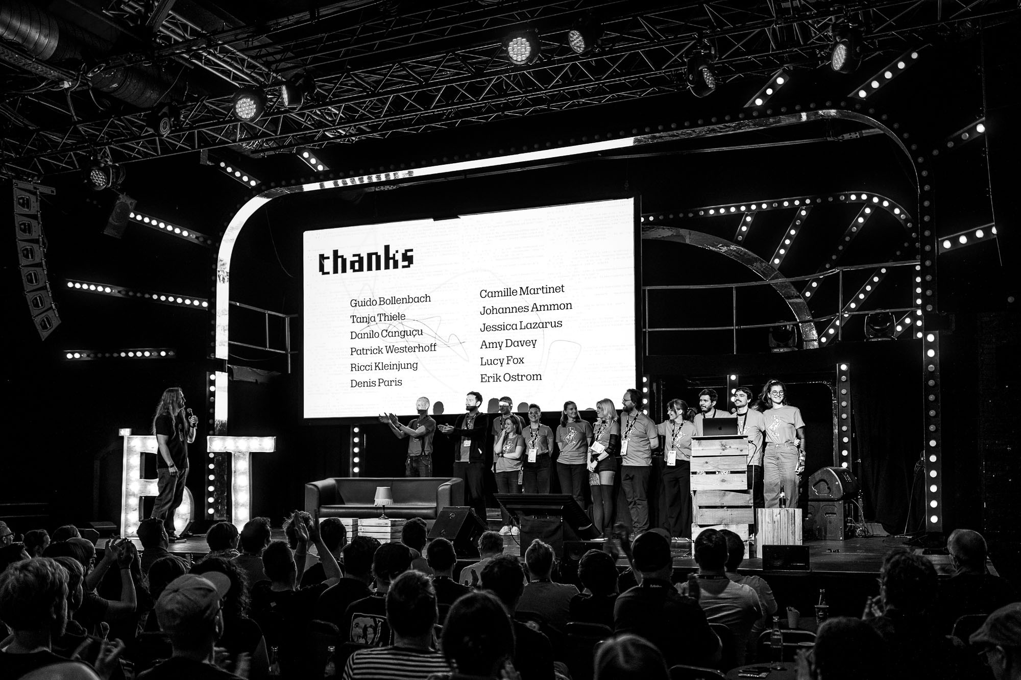 Black and white photo of Marc on stage thanking the beyond tellerrand team, who stand together to the right under a &ldquo;thanks&rdquo; slide listing twelve team members. The audience applauds in the foreground.