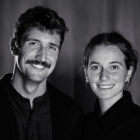 A portrait of Abel Reverter on the right and Katie Menzies on the left. Together they are known as Cabeza Patata, a design studio. Both are happily smiling into the camera