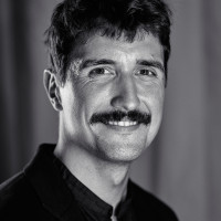 Portrait photo of Abel Reverter. He smiles and looks into the camera, wearing a black shirt.