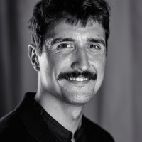 Portrait photo of Abel Reverter. He smiles and looks into the camera, wearing a black shirt.