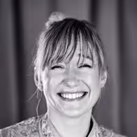 This is a portrait photo of Linda Liukas. She looks into the camera and has a big smile on her face. Looks very happy.