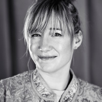 A portrait photo of Linda Liukas. She grins and has her head slightly bended to the left.