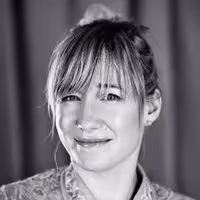 A portrait photo of Linda Liukas. She grins and has her head slightly bended to the left.