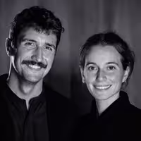 A portrait of Abel Reverter on the right and Katie Menzies on the left. Together they are known as Cabeza Patata, a design studio. Both are happily smiling into the camera
