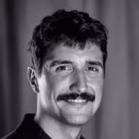 Portrait photo of Abel Reverter. He smiles and looks into the camera, wearing a black shirt.